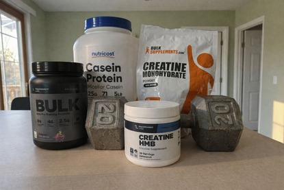 Workout supplements including protein powder, pre-workout, and creatine containers on a gym surface